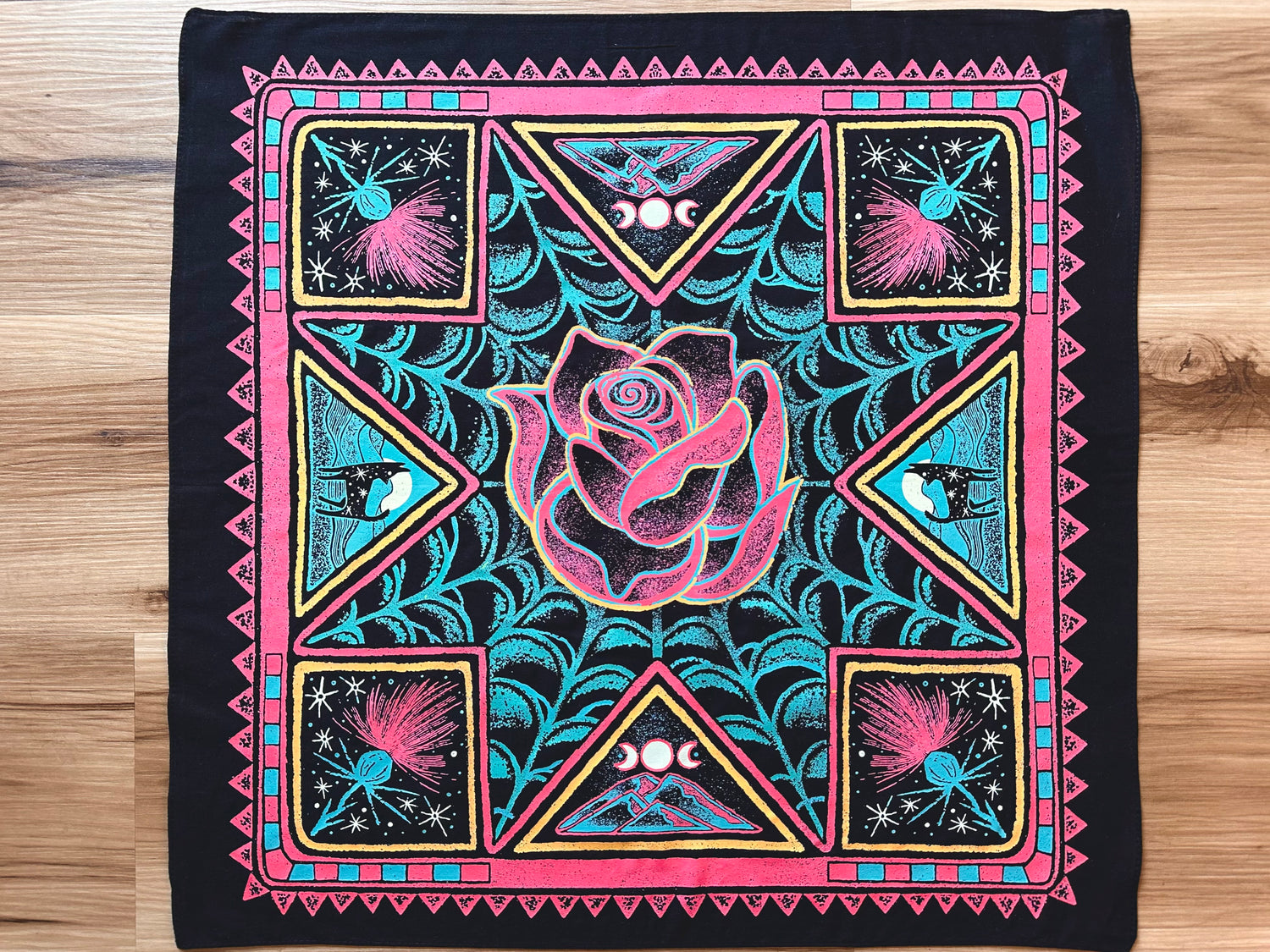 Decorative bandana with pink rose and geometric patterns on a wooden surface